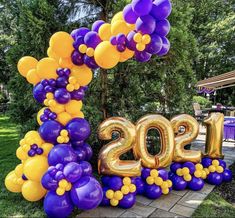 the number 20 balloon arch is decorated with purple and yellow balloons in front of a picnic table