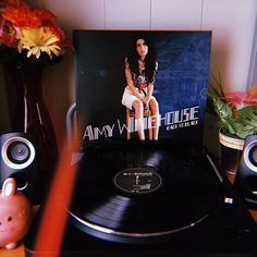 a record player sitting on top of a wooden table next to a vase with flowers