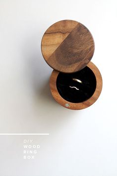 a wooden ring box sitting on top of a white table next to a black object