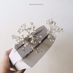 a person is holding a book with flowers on the pages and it's cover