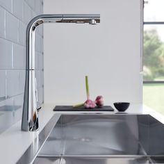 a stainless steel sink and faucet in a white kitchen with tile backsplash