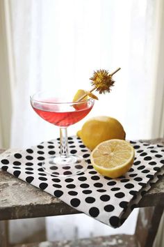 a drink in a glass next to a lemon on a polka dot napkin