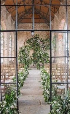 an outdoor wedding ceremony with flowers and greenery on the arch, surrounded by chairs