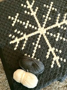 two balls of yarn sit on the floor next to a crocheted snowflake