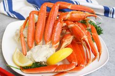 crab legs with lemon wedges and broccoli on a white plate next to chopsticks