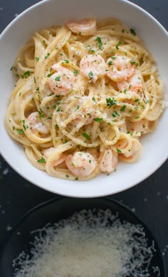 pasta with shrimp and parmesan cheese in a white bowl on a black table