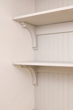 two white shelves in the corner of a room