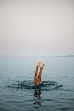 a person is swimming in the water with their legs above the water's surface