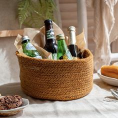 a basket filled with beer bottles sitting on top of a table next to plates and spoons