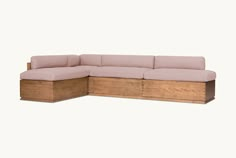 a wooden sectional couch sitting on top of a white floor next to a pink wall