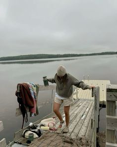 a woman standing on a dock next to a body of water