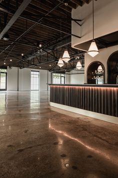 the inside of a building with several lights hanging from it's ceiling and windows