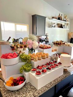 a table filled with lots of different types of food on top of white trays