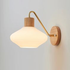 a wall light with a wooden arm and white glass shade on the back of it