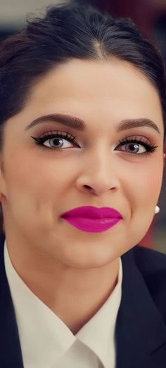 a woman in a suit and tie with pink lipstick on her lips is looking at the camera