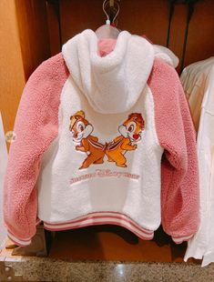 a pink and white teddy bear jacket hanging on a rack