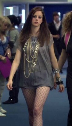 a woman in fishnet tights and heels walking through an airport lobby with other people