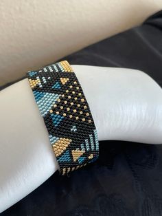 a beaded bracelet on a white mannequin's arm with black and blue beads