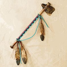 a wall hanging with feathers attached to it's sides and two arrows on the side