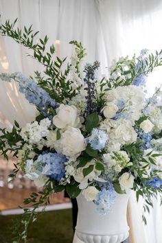 a white vase filled with blue and white flowers