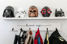 star wars masks are lined up on the wall above a sign that says hero up