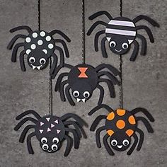 four spider decorations hanging from strings on the ground