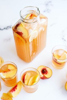 peach iced tea with sliced peaches and ice cubes on white marble countertop