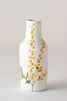 a white vase with yellow flowers painted on it