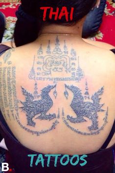 the back of a woman's shoulder with tattoos on it and an image of two dragon