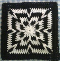 a black and white crocheted square on a table