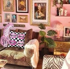 a living room with pink walls and pictures on the wall, leopard print couches