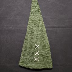 a crocheted green christmas tree hat with white crosses on the top and bottom