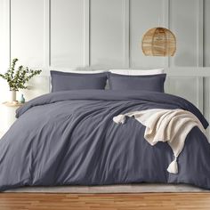 a bed with blue sheets and pillows on top of it in front of a white wall