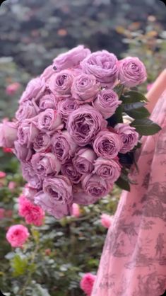 a woman holding a bouquet of pink roses