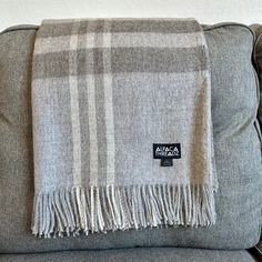 a gray plaid blanket sitting on top of a couch