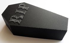 a black box with silver glittered dog tags on the front and sides, sitting on a white surface