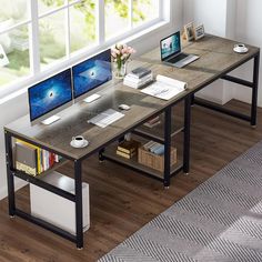 a computer desk with two monitors and a laptop on it in front of a window