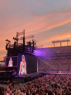 a large crowd is watching a concert on the big screen