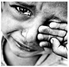 a black and white photo of a young boy holding his hands to his face while smiling