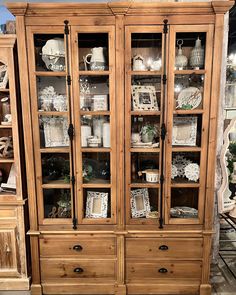 a wooden china cabinet with glass doors and drawers in a room filled with other furniture