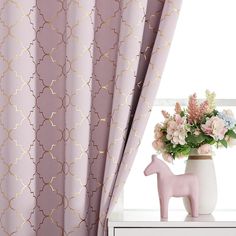 a vase filled with flowers next to a window covered in pink and gold patterned curtains