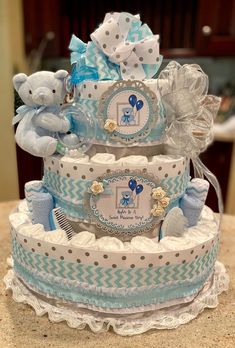 a three tiered baby shower cake with teddy bears on the top and blue accents