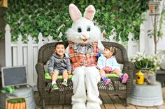 two children sitting on a bench next to a white rabbit statue and another child standing in front of it