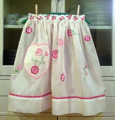 a pink and white dress hanging on a rack in front of a cabinet with dishes