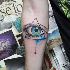 an eye tattoo on the arm with blue watercolor paint dripping down it's side