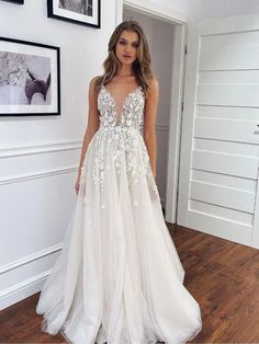 a woman standing in a room wearing a white dress with flowers on the skirt and an open back