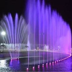 the colorful fountain is lit up at night with water shooting from it's sides