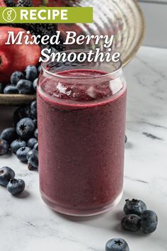 mixed berry smoothie in a mason jar with blueberries and strawberries on the side