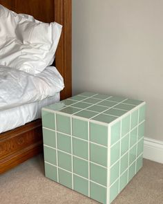 a small green box sitting on the floor next to a bed