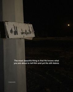 a sign that is on the side of a pole with words written below it at night